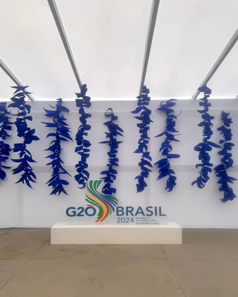 Diversas tiras de Côco azul penduradas em cachos na atrás do totem do G20 Brasil Rio Summit 2024, na entrada da Sala de Imprensa.